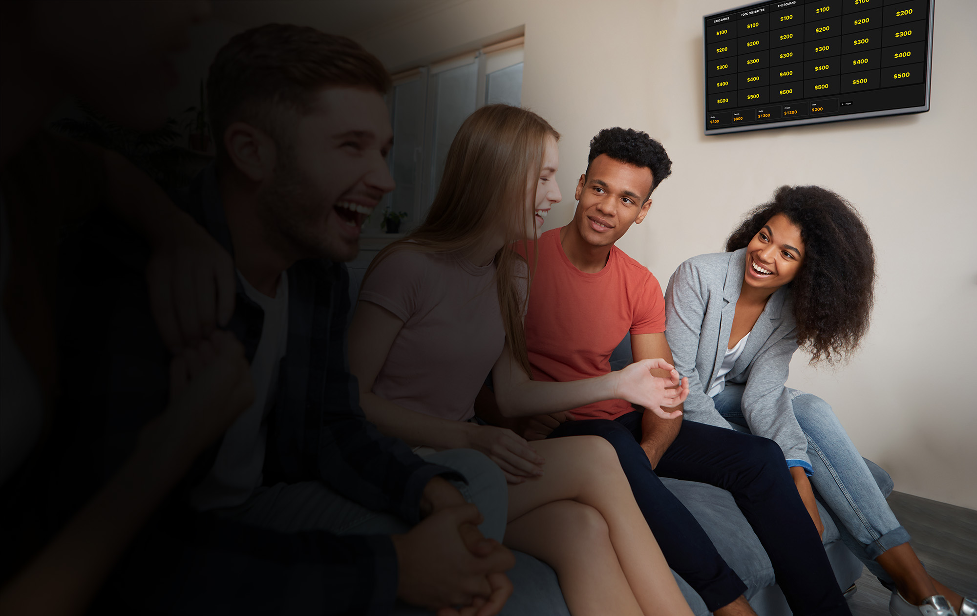 Friends laughing on a sofa while a trivia board is played on the wall screen
